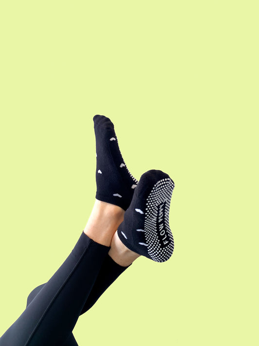 Black pair of Flow Peppy, New Zealand made ankle pilates and yoga grip socks with small white love hearts.